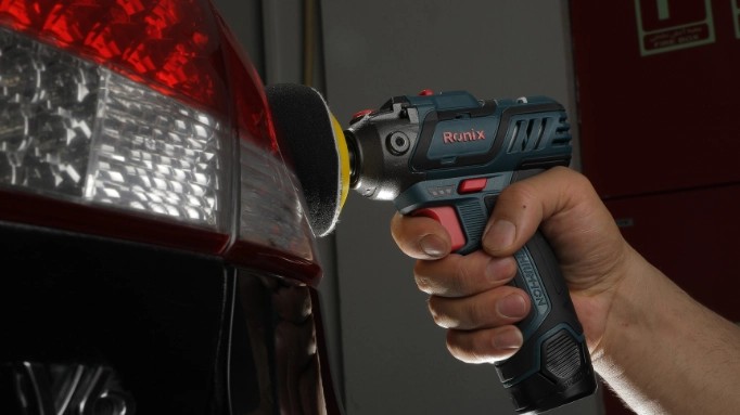 Close-up of a cordless polisher being used to polish the hood of a car, highlighting paint correction