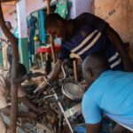 Mechanic in Eastern Cameroon working on a motorcycle, highlighting vocational skills and potential tool use.