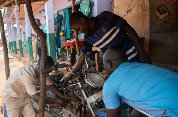 Mechanic in Eastern Cameroon working on a motorcycle, highlighting vocational skills and potential tool use.