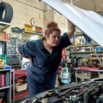 A mechanic inspecting a car engine for maintenance and repair deductions.