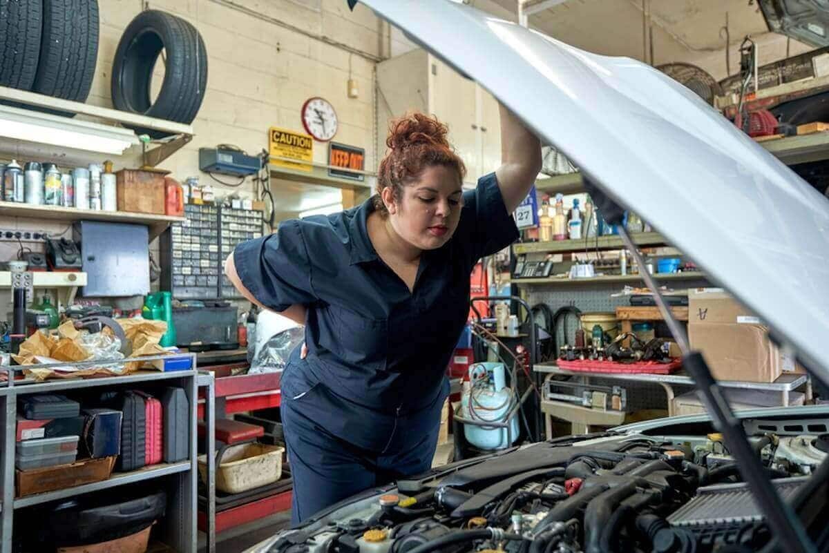 A mechanic inspecting a car engine for maintenance and repair deductions.