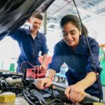 Mechanic using an air compressor to inflate a car tire with essential tools nearby