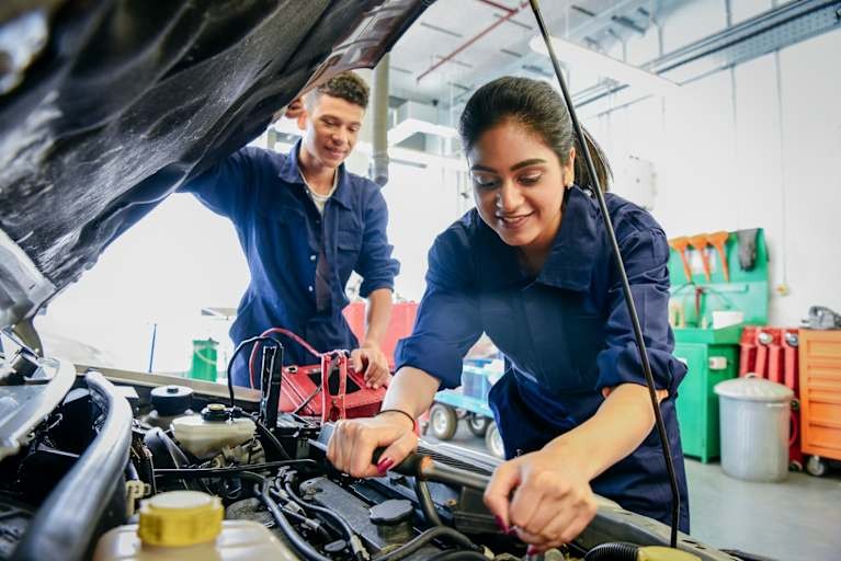 Mechanic using an air compressor to inflate a car tire with essential tools nearby