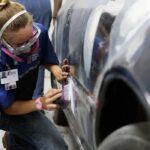 Professional auto body technician using a wrench to dismantle a car part