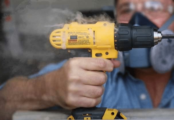 A drill overheating and smoking, indicating the need to cool down, emphasizing power tool maintenance.