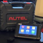 Mercedes Streeter holding an Autel MaxiPRO MP808BT diagnostic scan tool in a garage setting, showcasing its portable tablet design.