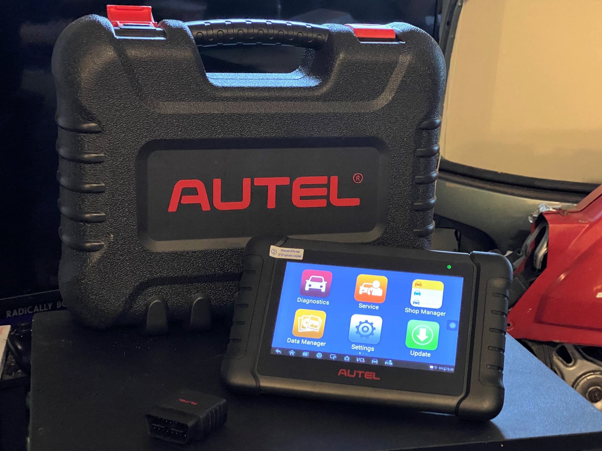 Mercedes Streeter holding an Autel MaxiPRO MP808BT diagnostic scan tool in a garage setting, showcasing its portable tablet design.