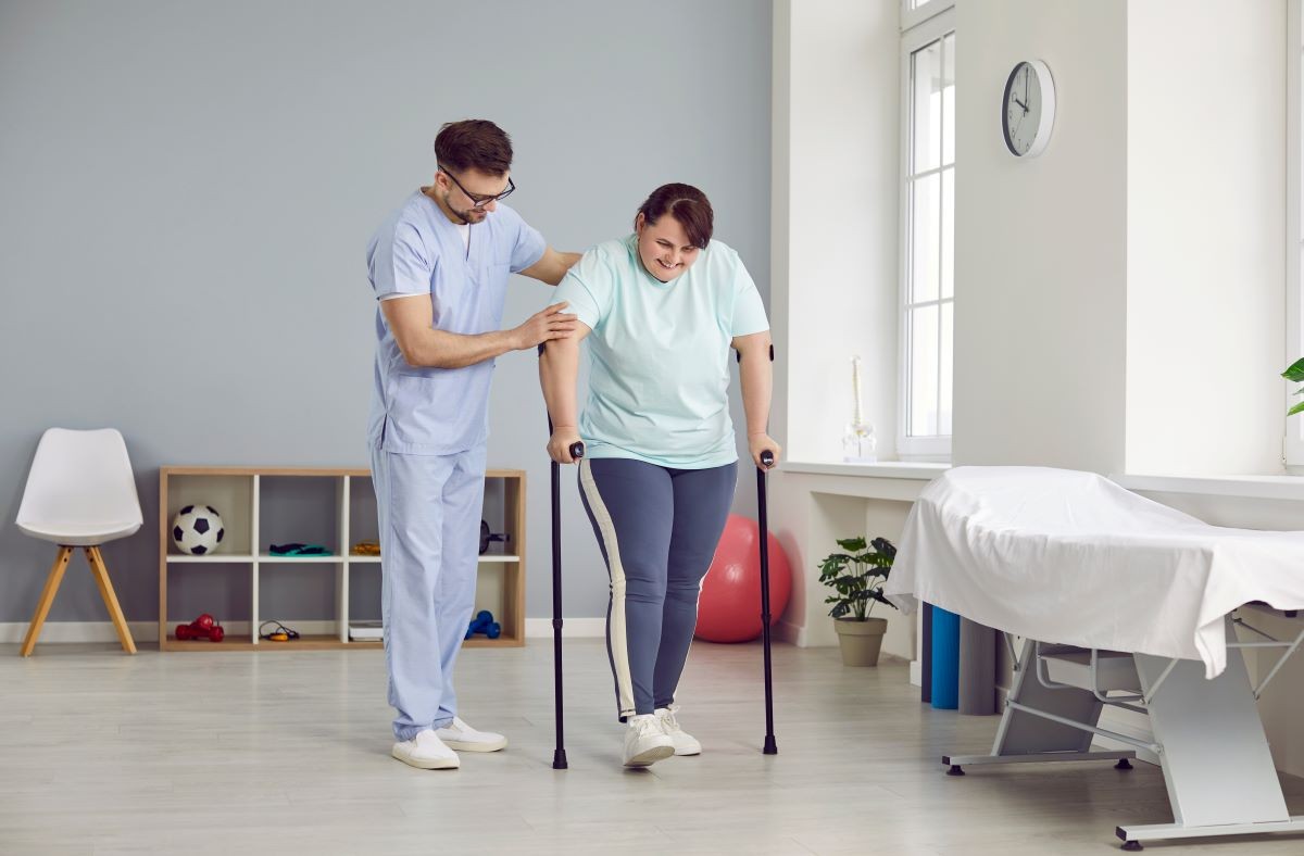 A caregiver assisting a senior patient with walking exercises at home, emphasizing fall prevention in home health care.