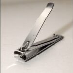 Close-up of stainless steel nail clippers trimming fingernails