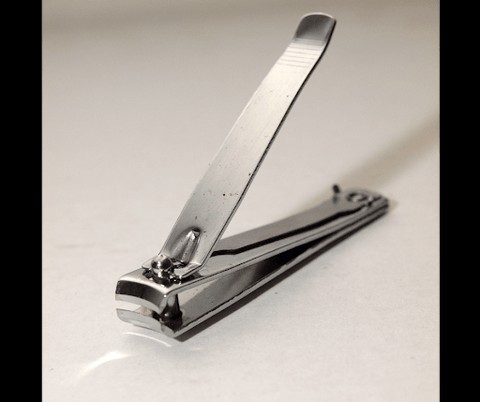 Close-up of stainless steel nail clippers trimming fingernails