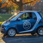 Front three quarter view of a silver Smart car with business decals on the side