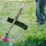 Professional string trimmer in action, cutting grass edges for lawn maintenance.