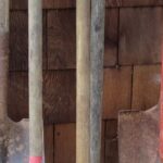 Close-up of a person cleaning a wooden handle of a garden tool with soapy water and a brush