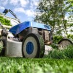 Red lawn mower cutting green grass in a field