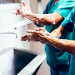 A nurse demonstrates proper hand hygiene by washing her hands.