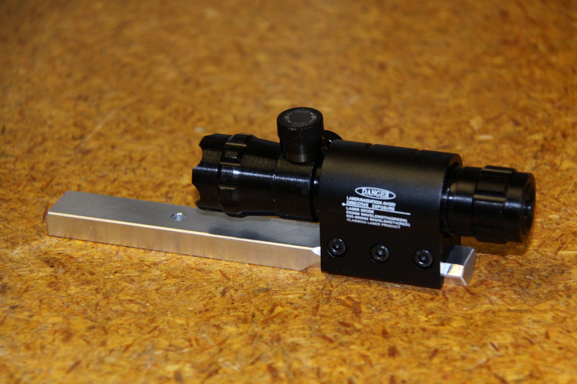 alt text: Laser sight mounted on a square tube with custom mounting hardware.